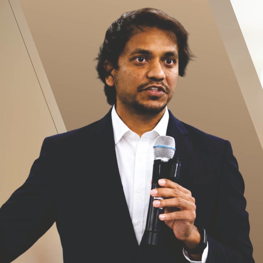 Hari Kishan speaking on stage with a microphone